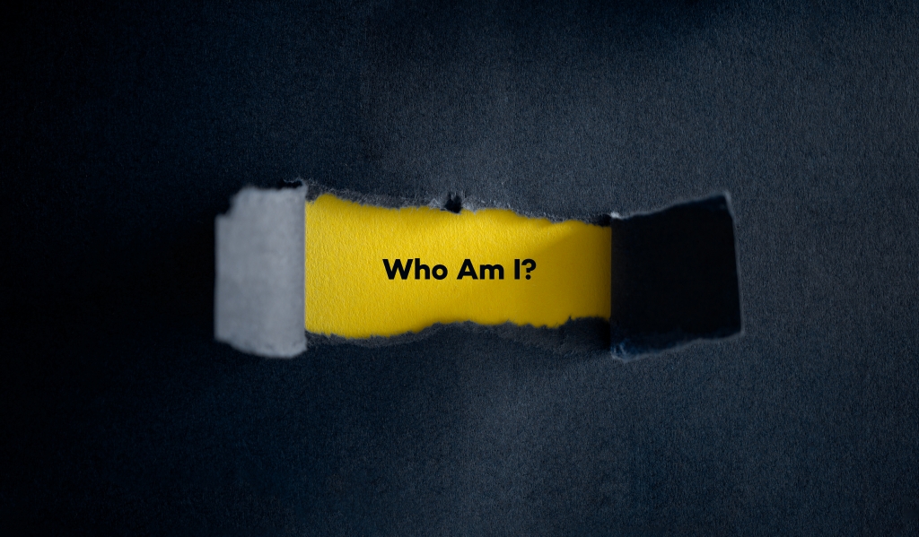 Paper peeling back to reveal "Who Am I?"